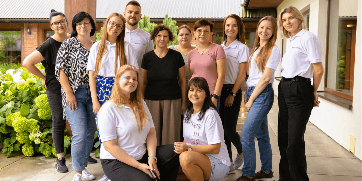 Grupa uśmiechniętych osób stojących przy budynku
